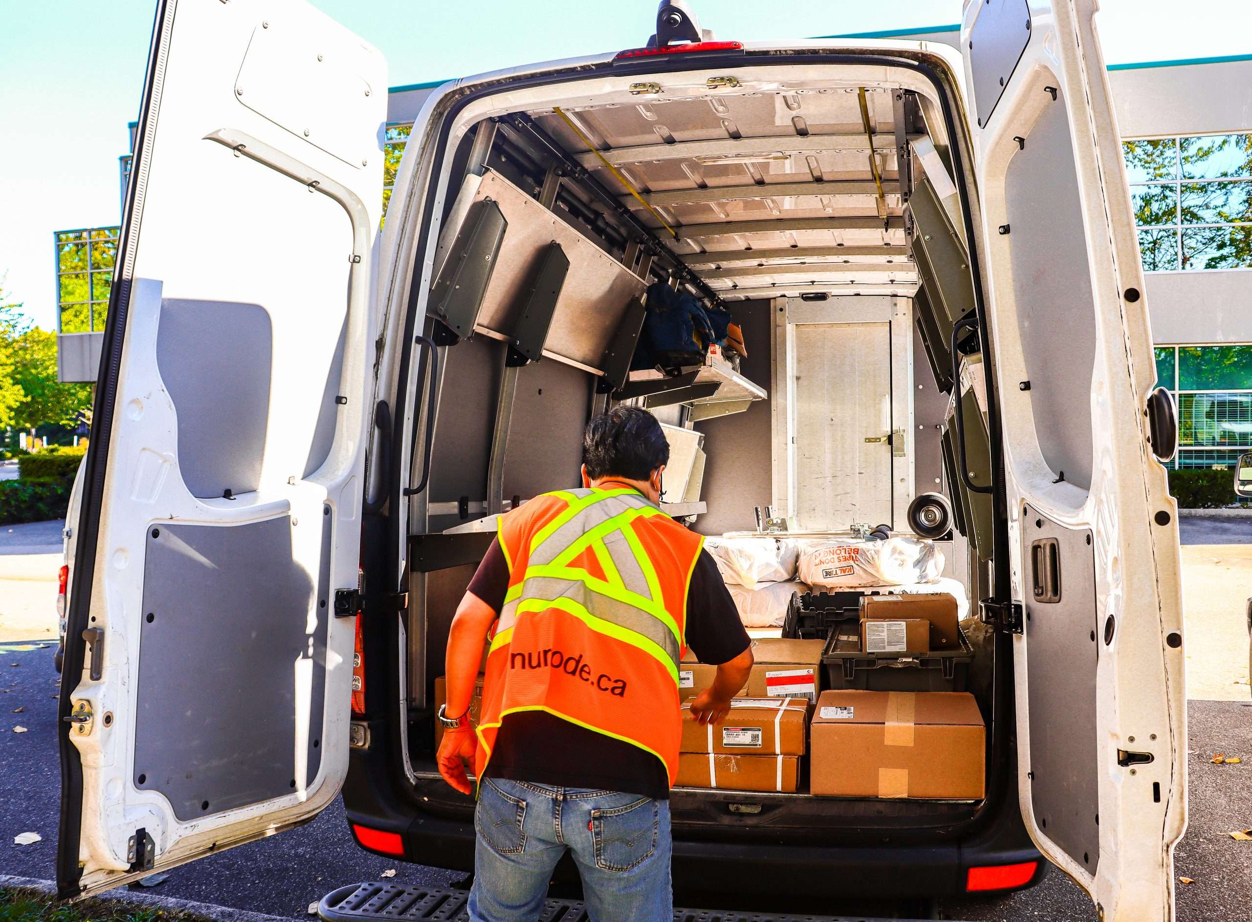 employee unloading the packages off the numode delivery white van