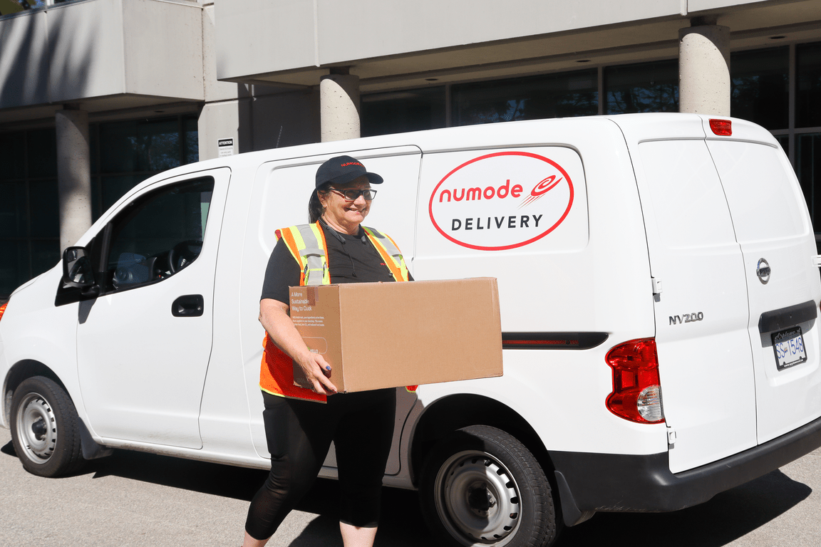 Employee carrying a box in front of our van for Vancouver Courier services