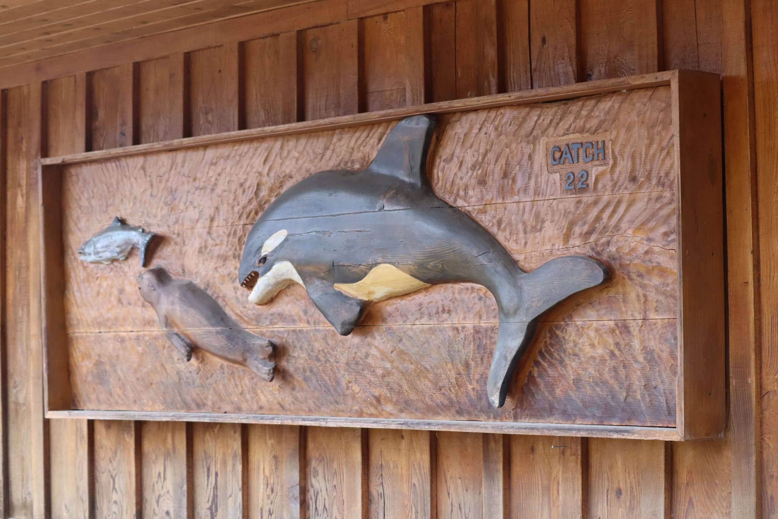 local wood art with a fish, a seal, and an orca on it